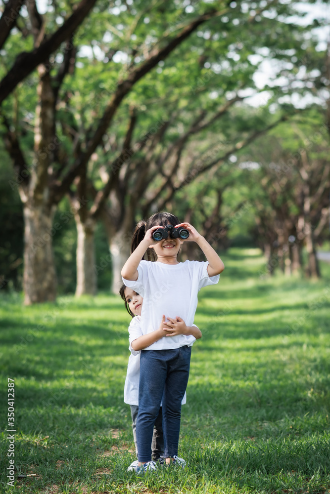 little girl use binoculars in summer garden on warm day outdoors. little girl use binoculars in summer garden on warm day outdoors.