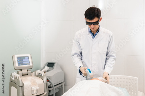Male cosmetologist doing laser epilation treatment in spa salon