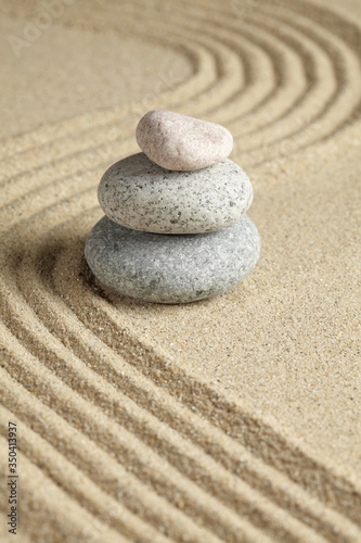 Three stones stacked on raked sand