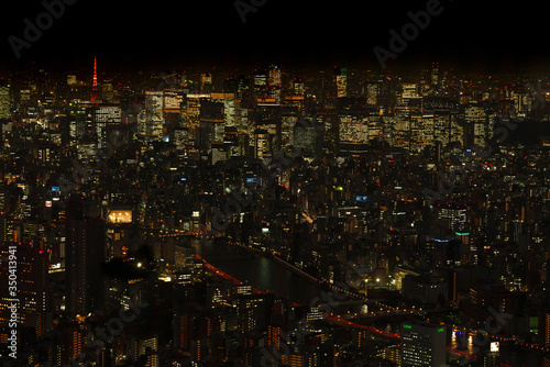 Tokyo night view from Tokyo Sky Tree, buildings have lights on and Tokyo Tower is lit up in red.