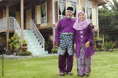 Muslim couple standing outside their house
