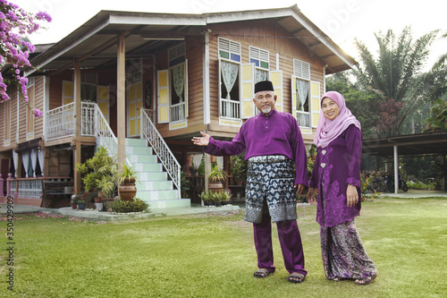 Muslim couple standing outside their house