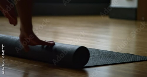 Female yoga student unravels yoga mat in yoga studio getting ready to do a yoga class
