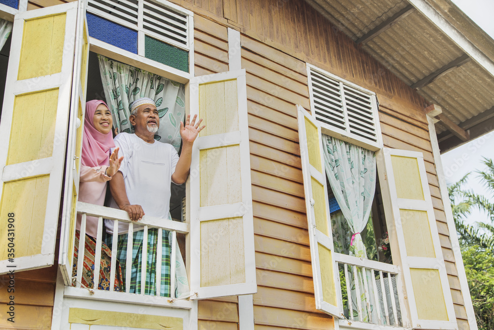 Senior couple waving from house window