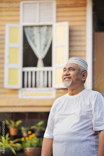 Senior man standing in front of wooden house