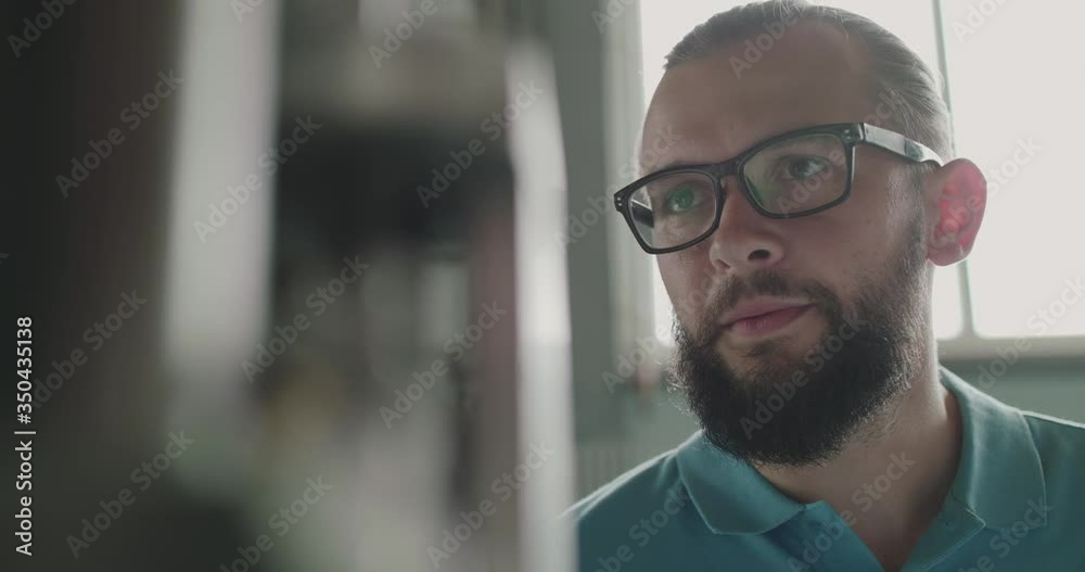 Portrait of engineer in glasses looks at machine tool attentively on factory Portrait of engineer in glasses looks at machine tool attentively on factory