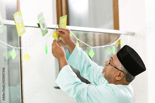 Muslim man decorating home for Eid al-Fitr