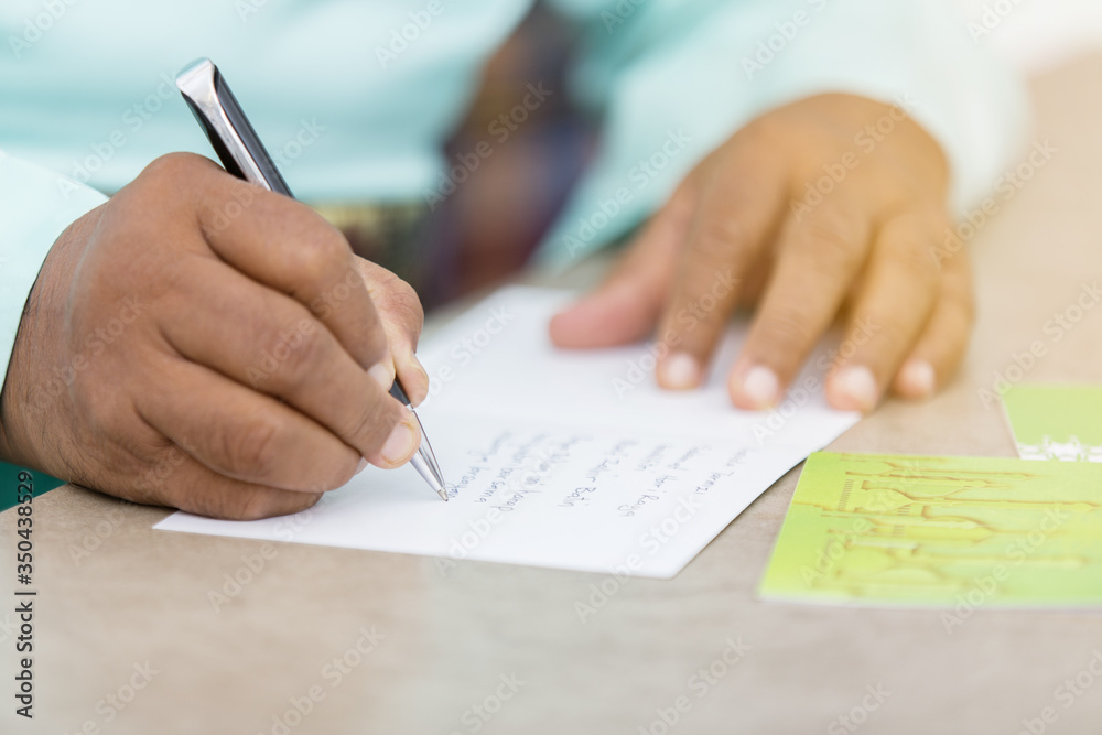 Muslim man writing greeting cards for Eid al-Fitr Muslim man writing greeting cards for Eid al-Fitr