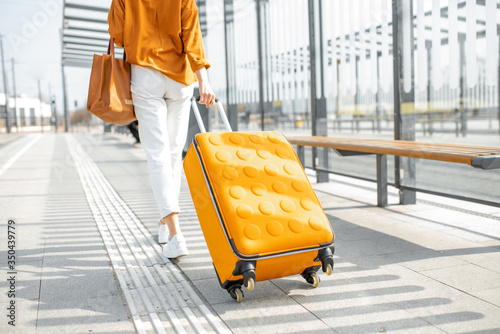 Young female traveler with a luggage at the transport stop