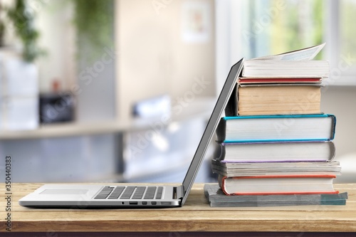 Stack of books with a modern laptop on the table