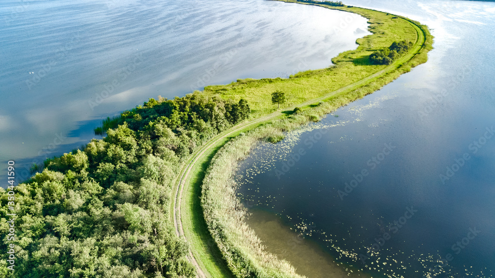 Aerial drone view of path on dam in polder water from above, landscape and nature of North Holland, Netherlands
