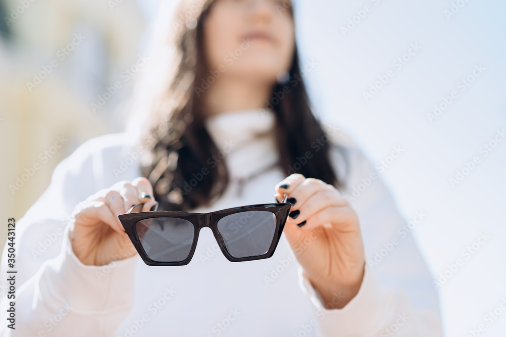 Brunette on a blurred background, in her hands clearly visible sunglasses, close-up Brunette on a blurred background, in her hands clearly visible sunglasses, close-up