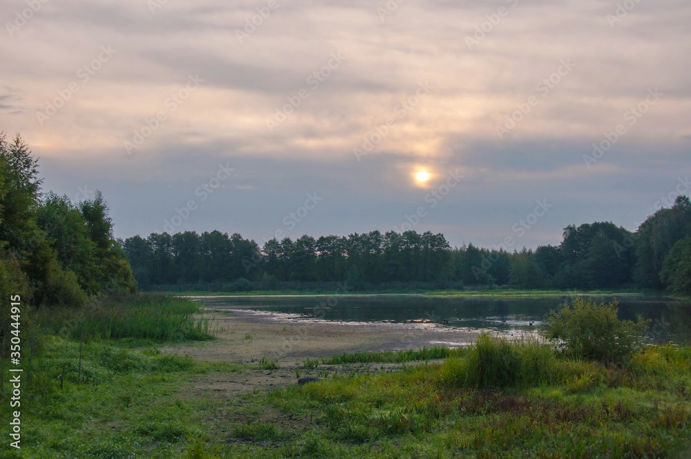 Cloudy dawn over a forest lake. Moscow region. Russia.