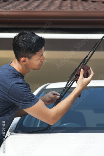 Man cleaning windshield wiper of his car