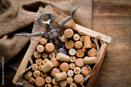 Wine corks of different sizes and a corkscrew standing upright on an old wooden surface. Background for liquor.