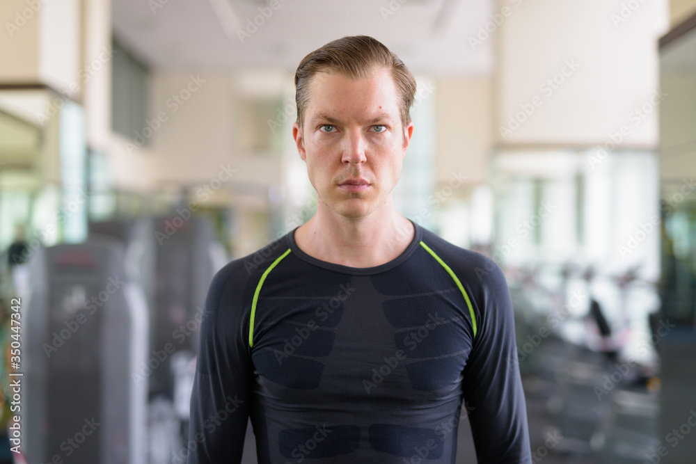 Portrait of young handsome man thinking at the gym during covid-19