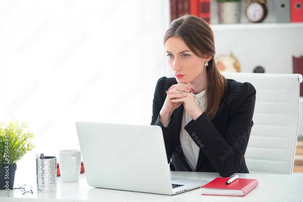 Young woman working at a desk with a laptop in an office. Female business, distant work Young woman working at a desk with a laptop in an office. Female business, distant work