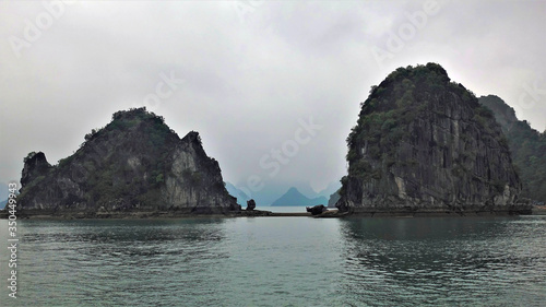 Rain and fog at Halong Bay. The islands are sheer cliffs covered with green vegetation. Far in the fog, the outlines of many other islands. Silence.