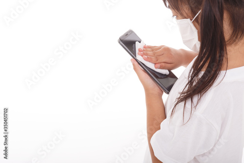 Asian girl wear mask cleaning smartphone screen with alcohol.on white background. Concept of Cleaning dirty screen phone for disease prevention from bacteria.