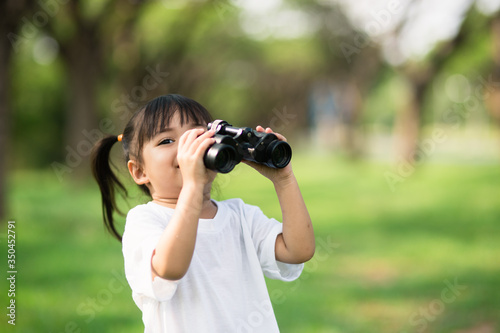 Happy child girl playing with binoculars. explore and adventure concept