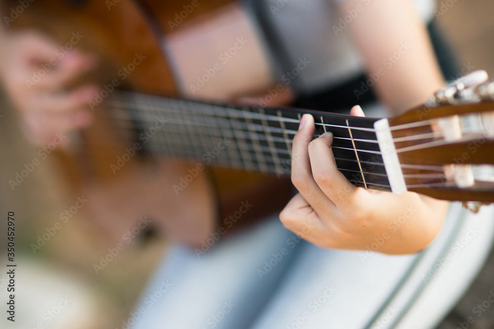 Obraz premium Lovely girl,playing guitar, singing ,music or happiness concept, sunset warm light tone effect.