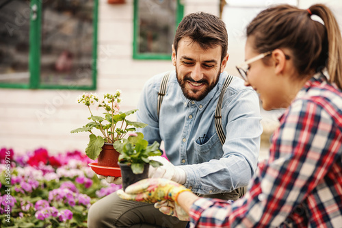 Entrepreneurs are crouching and holding pots with flowers and talking about different sorts of flowers. photo