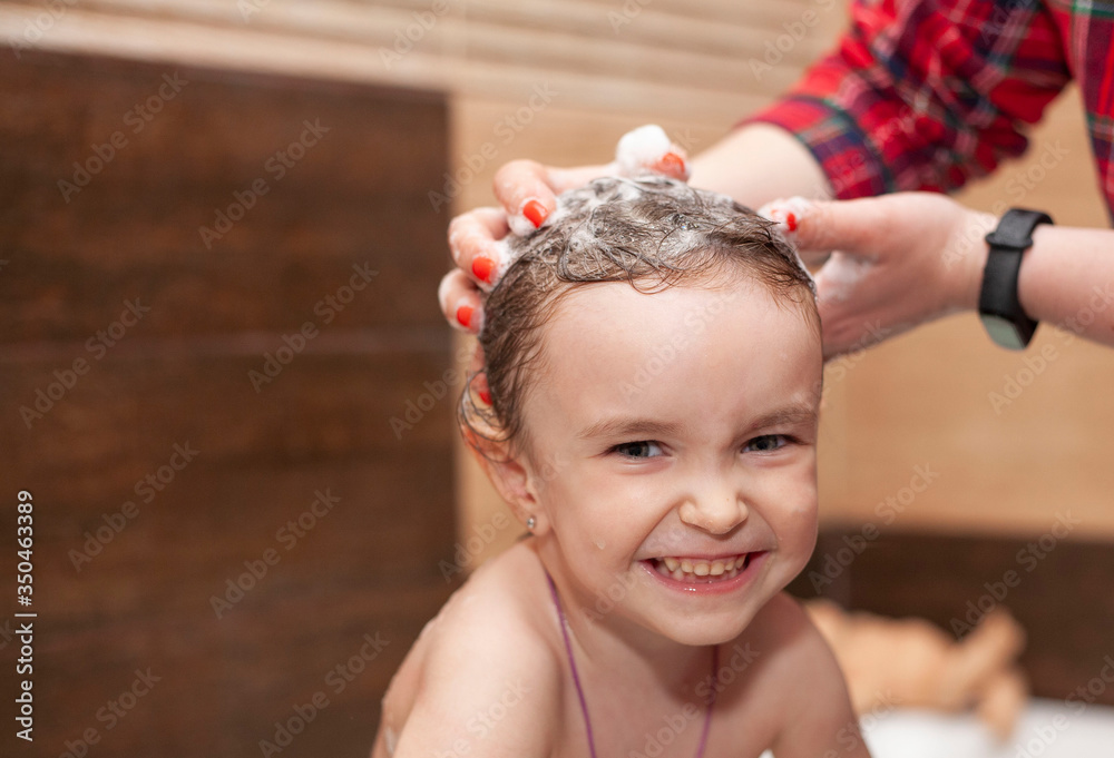 Mom washes the baby’s head. Women's hands are washing the baby’s head