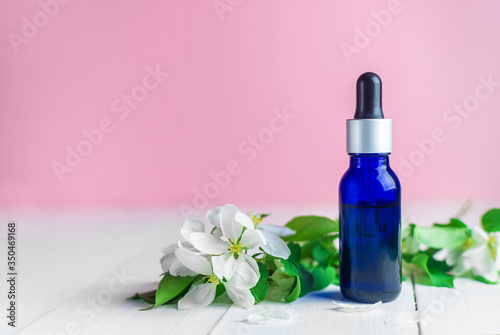 cosmetic oil in blue bottle and white flowers