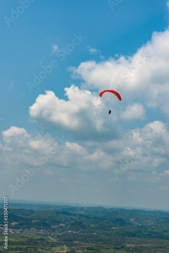 Outdoor city green hill scenery and paragliding