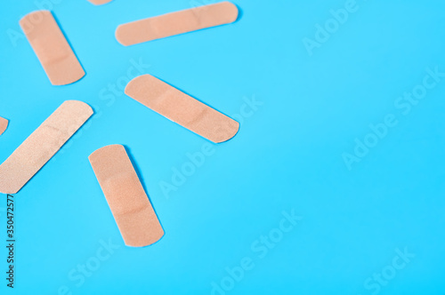 Scattered sticky medical patches on blue background. Healthcare concept