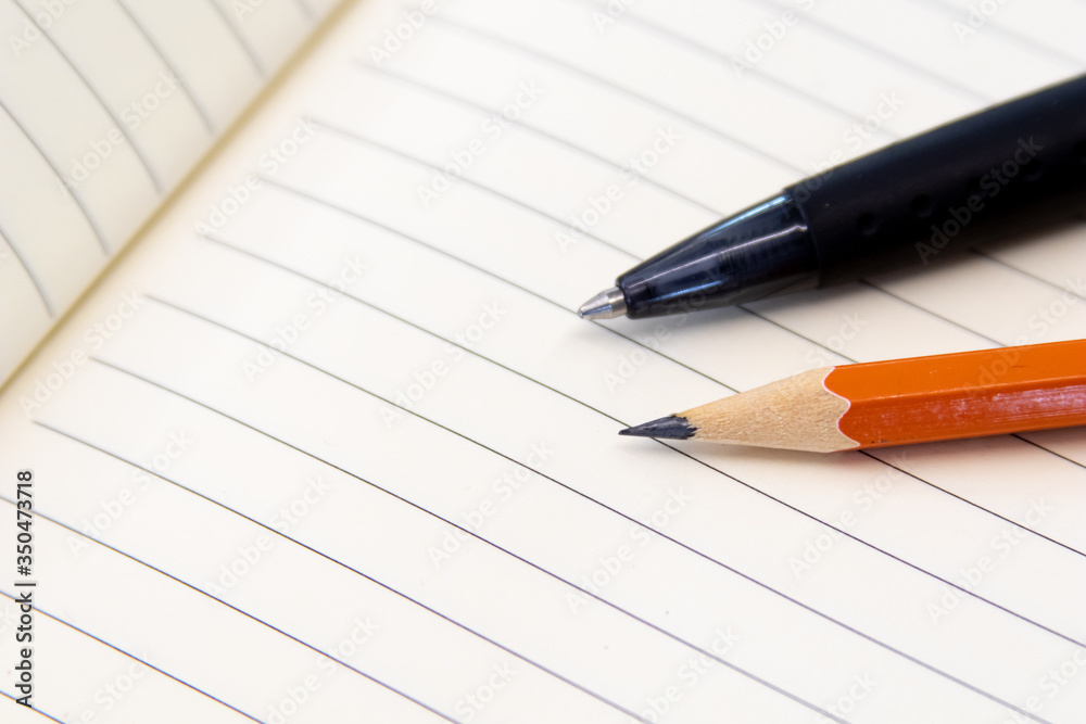 Educational tools, Pencil and pen on notebook with rows. Office and school tools for production. Image for lawyer, business and activities with notes Educational tools, Pencil and pen on notebook with rows. Office and school tools for production. Image for lawyer, business and activities with notes