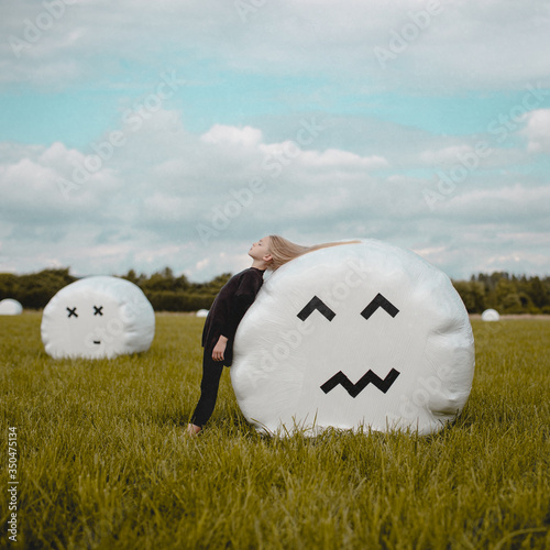 Girl with eyes closed leaning on hay bale in field