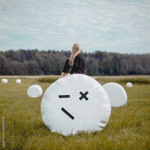 Girl looking at view while sitting on hay bale in field