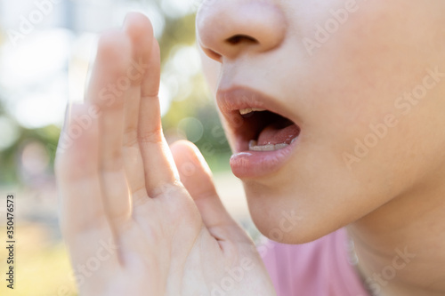 Close up,Asian young woman raised her hand near her mouth to whisper or speaks softly and gossip,child girl telling a secret or talking in a low voice,sharing a secret,whispering and gossiping concept photo