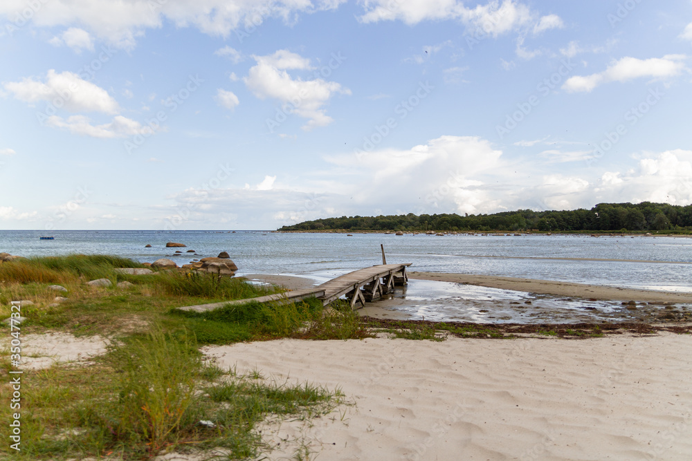 An empty deserted calm sandy beach on a sunny day with wooden bridge An empty deserted calm sandy beach on a sunny day with wooden bridge