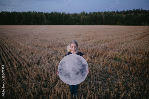 Portrait of girl with eyes closed holding paper moon in field