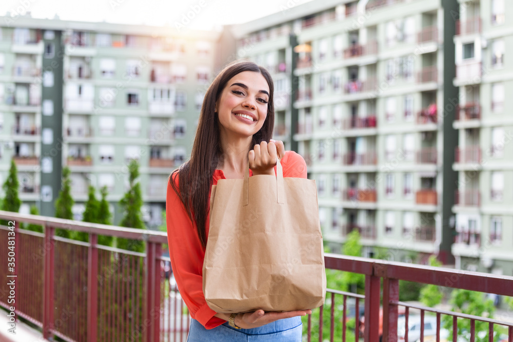Woman Doing Shopping For Senior Neighbors. Young beautiful woman holding take away paper bag from delivery Woman Doing Shopping For Senior Neighbors. Young beautiful woman holding take away paper bag from delivery