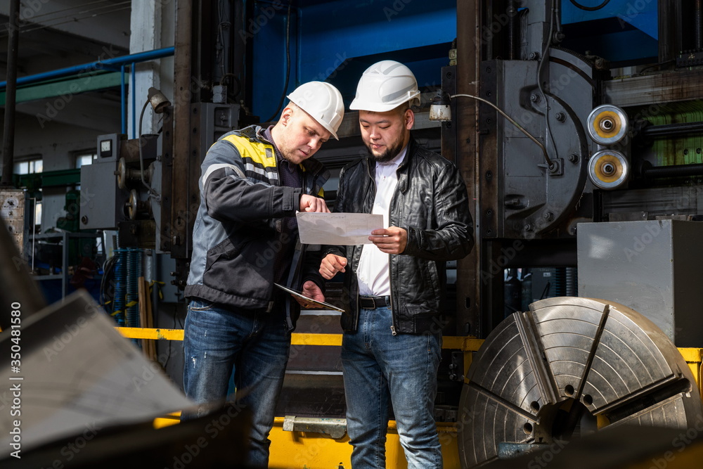 Two young engineers at a modern factory. The photo illustrates new technologies and production. Two young engineers at a modern factory. The photo illustrates new technologies and production.