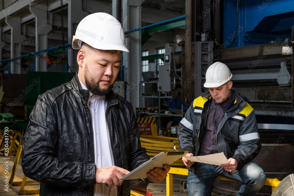 Young asian engineer at modern plant. The photo illustrates new technologies and production.