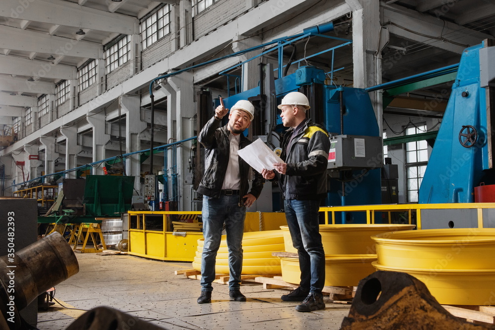 Obraz premium Two young engineers at a modern factory. The photo illustrates new technologies and production.
