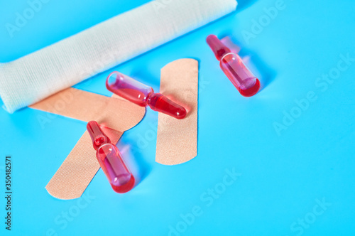 Heap of sticky medical patch near red vaccine and bandage on blue background. Healthcare concept