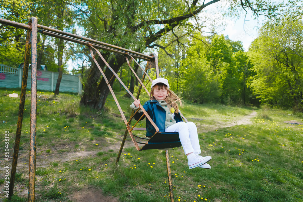Cute preschool laughing girl swinging on a swing at the playground. Cute preschool laughing girl swinging on a swing at the playground.