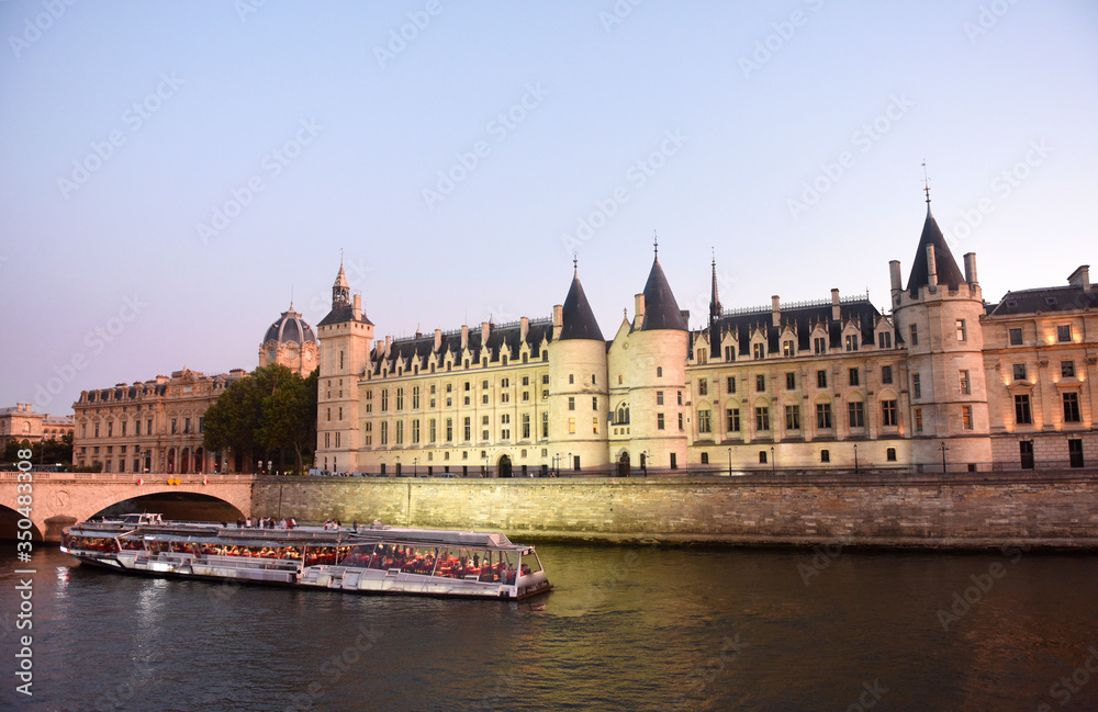 Tourist ship on the Seine river and Conciergerie building at the background in Paris, France.