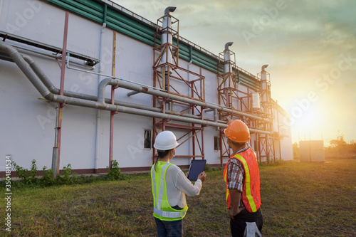 engineer discusses technical documentation with his help in the territory of a modern plant.Engineers working in the power plant area