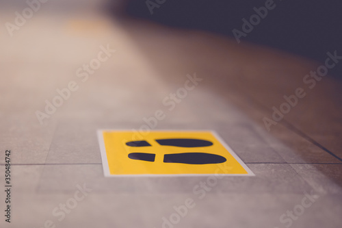 View of footprint sign for stand in lift. Social distancing with COVID-19 coronavirus crisis.yellow footprint sign with text caution social distance, Social distancing the elevator (Lift) in hospital.