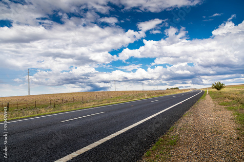 A lonesome road leading through the Kosciuszko national park in the Snowy Mountains, a part of the Australian alps, during a cloudy day in summer.