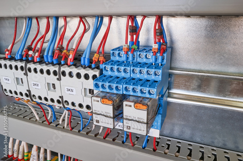 Two electrical intermediate relays and three contactors or magnetic starters in the electrical Cabinet. Electrical wires and cables are connected to the relays and contactors. Assembly, maintenance.