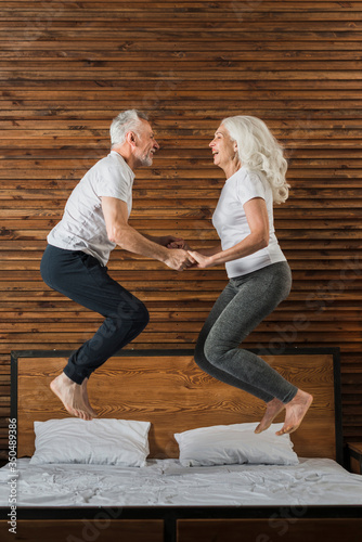 Senior couple jumping in bed