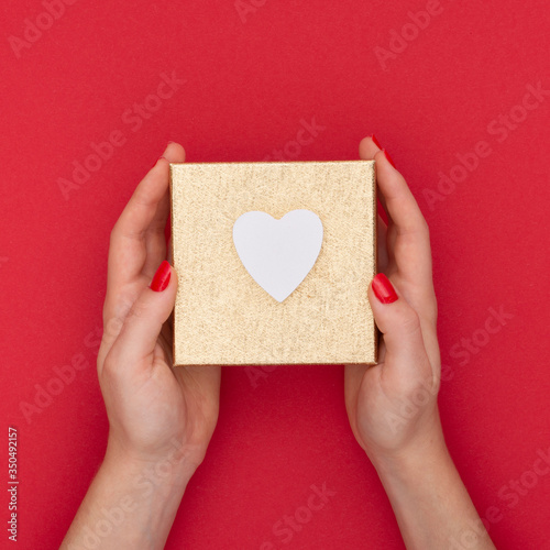 Close-up woman holding present box with red background