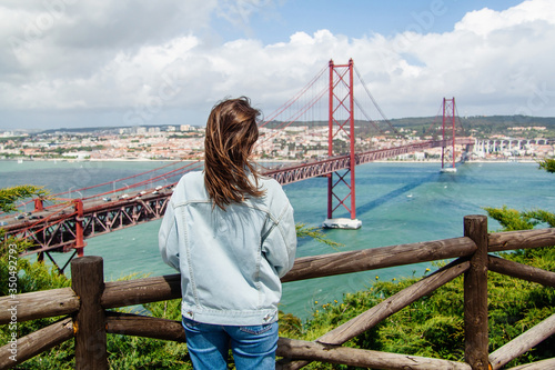 Young girl looking at the panoramic view of 25th of April Bridge (Ponte 25 de Abril), Lisbon, Porugal